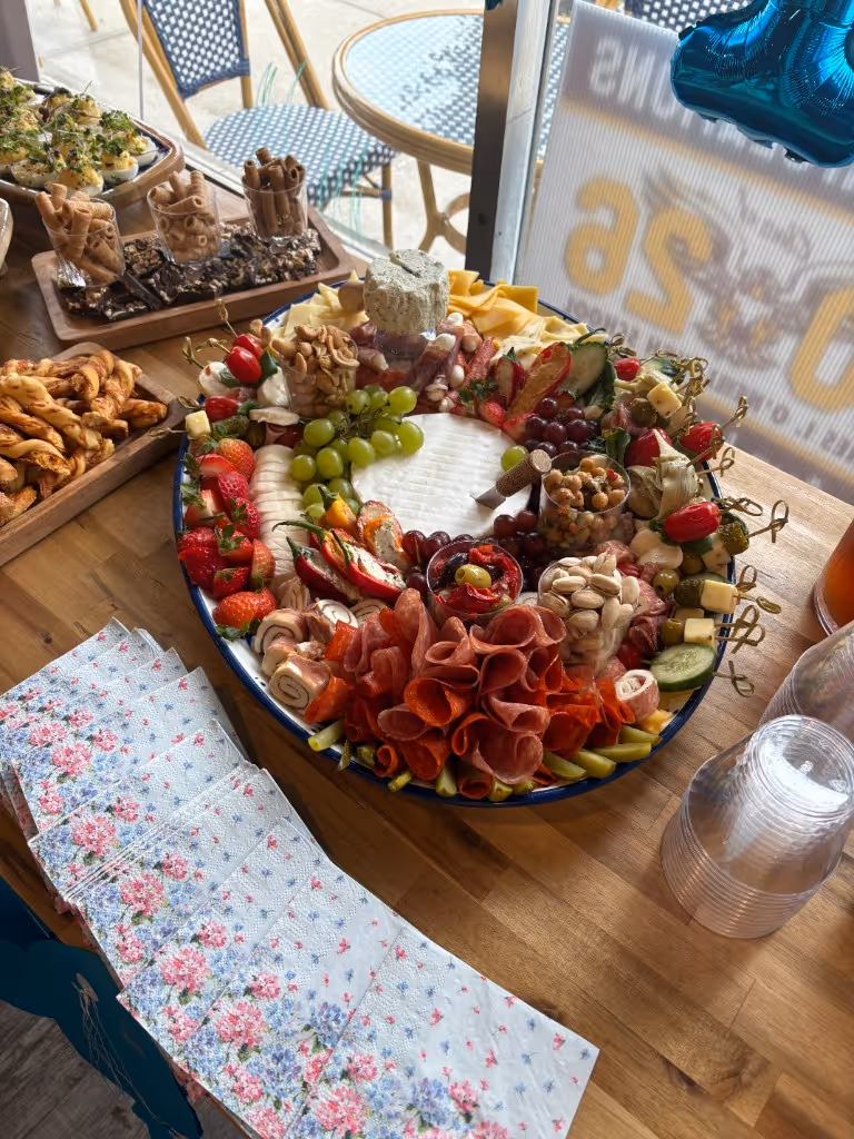 Large charcuterie board with cured meats, cheeses, grapes, strawberries, and nuts