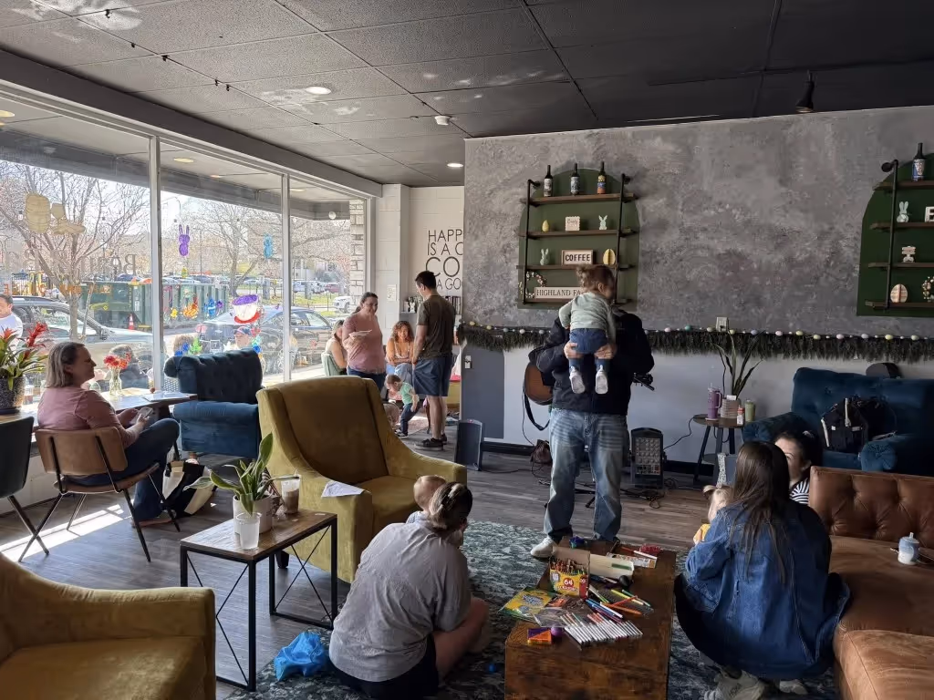 Spacious lounge with colorful armchairs, rug, and guests enjoying the cafe